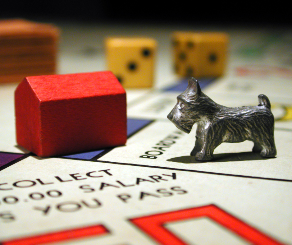 A red house and a small metal dog at the Corner of Broadway & Go on the Monopoly Board