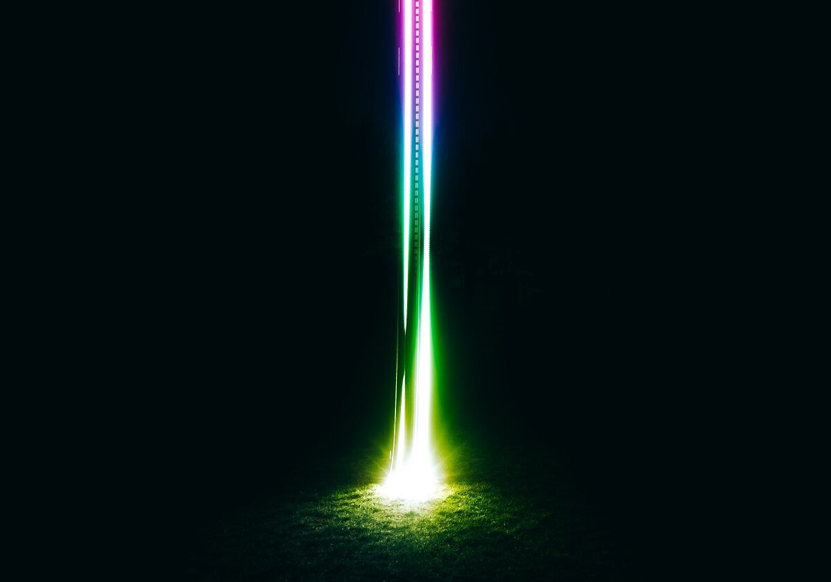 A vertical shaft of multicoloured light against a black background