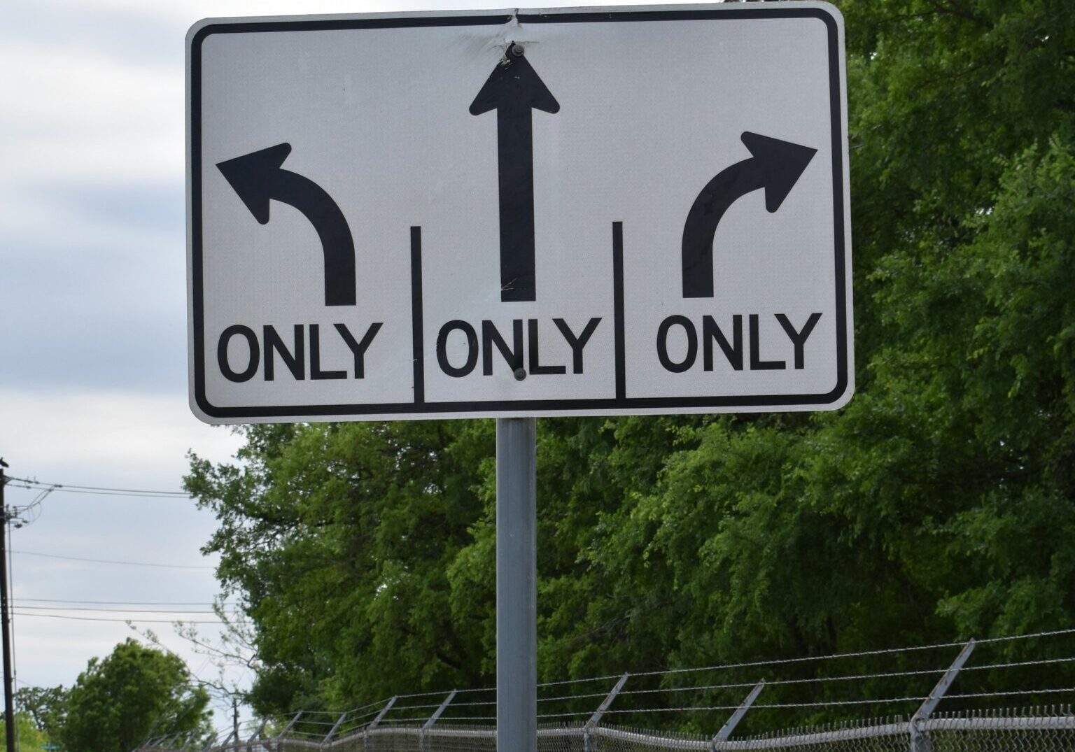 A roadsign showing arrows pointing in three different directions, each with the word only underneath it